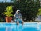 Man in aqua menthe hoodie sitting on swimming pool, whith cellphone.
