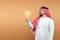 A man Arab holds a national costume holding a light bulb in his hand on a beige background. Concept idea, thought