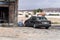 man in Arabic clothes pumps up the wheel of an old car near a garage with tire service