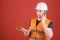 Man, architect in helmet supervises construction on phone, red background. Negotiation concept. Engineer, architect