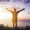 Man with arms outstretched celebrating in beautiful inspiring sunset