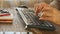 Man arms typing on keyboard at natural hardwood desk