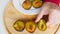 A man arranges sliced plum halves on a yellow wooden board. Large juicy dark blue plums on a white plate. Beautiful ripe fruits