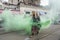 Man as witch with green smoke-bomb at carnival