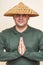 Man with Asian straw hat, clasped palms hand sign. Buddhism.