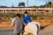 Man assisting a child with disabilities in an assisted equine therapy session.