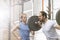 Man assisting friend in lifting barbell at crossfit gym