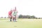 Man assisting woman aiming ball on golf course against clear sky