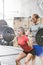 Man assisting woman in lifting barbell in crossfit gym