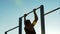 Man athlete training on chin-up bars outdoors, physical strength and sport