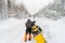 A man, an athlete in a warm sports suit stands and pushes a snowmobile