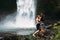 A man of athletic build kisses a beautiful girl at the waterfall. Honeymoon trip. Declaration of love. A couple in love on a