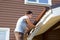 Man attaches gutter on roof of the porch