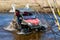 The man on the ATV rides on the river with a splashing water