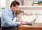 Man With Baby Working From Home Using Laptop