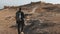 Man with backpack explores ancient ruins. Relaxed Caucasian male tourist walks on summer desert rocks and sand Israel 4K