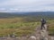 Man backpack hiker at Kungsleden trail admiring nature of Sarek in Sweden Lapland with mountains, river and lake, birch and spruce
