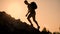 A man with a backpack rises to the top of the mountain at sunset. Silhouette of the person at sunset. Healthy Active