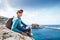 Man with backpack sits on the rocky seaside