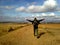 Man with backpack spreading arms and walking in field. Camino de Santiago concept. Pilgrimage concept.