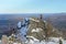 Man with backpack trekking in mountains at winter. Hiker climbing to the rock covered with snow.