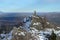 Man with backpack trekking in mountains at winter. Hiker at the top the rock covered with snow.