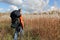 Man with a backpack walking across a field with tall grass