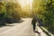 A man with backpack walking alone on empty road in the morning with bright sunlight