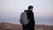 Man with backpack walks in desert. Slow motion. Young male wanders alone in dusk wilderness. Scenic mountain sky. Israel