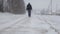 A man with a backpack walks down the street, a heavy snowfall winter, a blurry