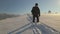 Man backpacker hiking snowy mountain hillside on cold winter morning.