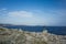 Man with bag on back standing on rocky coast in Croatia looking at beautiful blue ocean