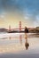 Man on Baker Beach and a magnificent view of the Golden Gate Bridge at dawn