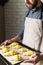 Man baking croissants at home, holding oven tray with uncooked layered dough