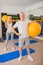 Man with a ball and a woman with dumbbells exercising together in gym