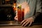 Man at bar sets fire to glass of tomato juice cocktail garnished with slices