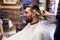 Man and barber with brush cleaning hair at salon