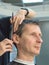 Man in barber chair, hairdresser haircut his hair.