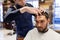 Man and barber cutting hair at barbershop