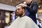 Man and barber cutting hair at barbershop