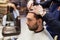 Man and barber cutting hair at barbershop