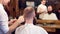 Man barber cutting hair with scissors in male hair salon. Cropped male client sitting back. Blurred reflection in mirror