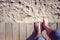 Man barefoot stepping off boardwalk onto the beach sand