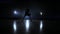 A man with a basketball on a dark basketball court against the backdrop of a basketball ring in the smoke shows