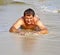 Man in bathingsuit is lying at the beach and enjoying the saltwater with tiny waves