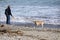 Man On Beach Throwing Stick For Dog