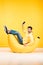 Man on bean bag chair holding smartphone on yellow