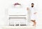 Man with beard in bathrobe enjoys morning while standing near piano. Talented musician concept. Man serious stands and