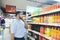 A man with a beard buys food in a supermarket. A young man chooses a beverage at a supermarket.