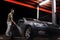 A man with a beard or car washer washes a gray car with a high-pressure apparatus at night in a car wash